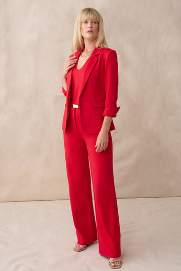Woman wearing a red suit against a beige background