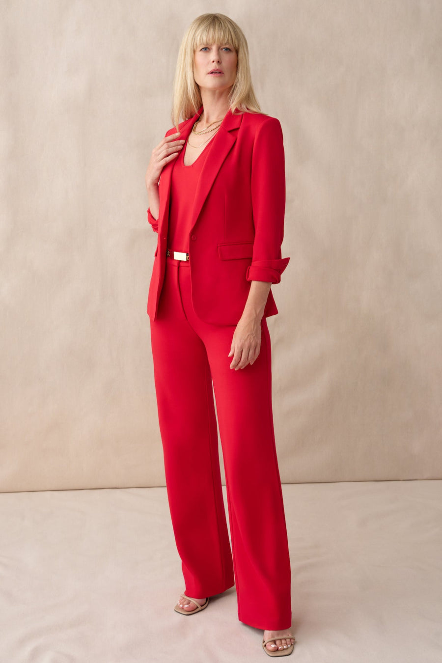 Woman wearing a red suit against a beige background