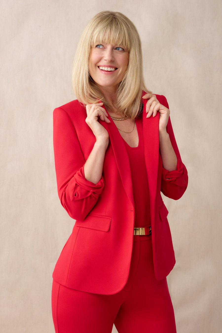 Woman wearing a red suit against a beige background