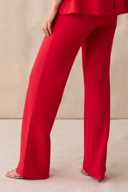 Woman wearing a red outfit standing against a beige background