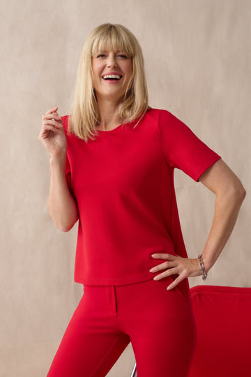 Woman in a red outfit posing against a beige background