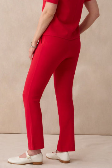 Woman wearing a red outfit standing against a beige background