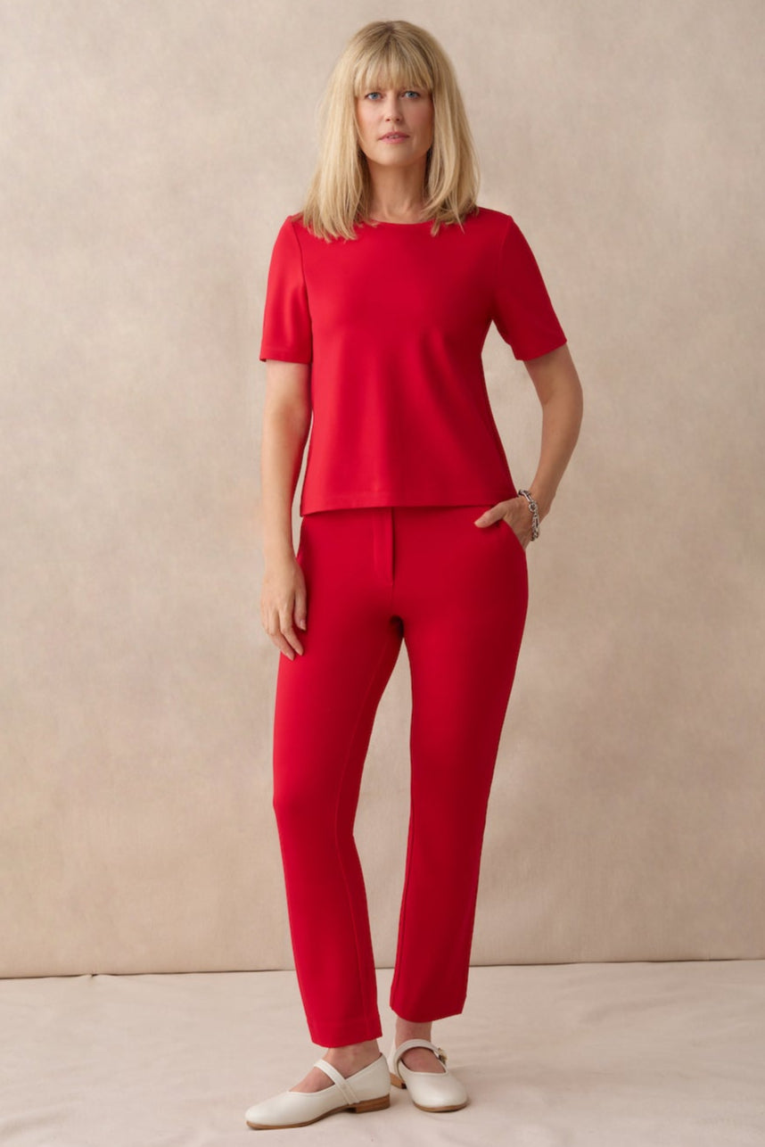 Woman wearing a red outfit standing against a beige background