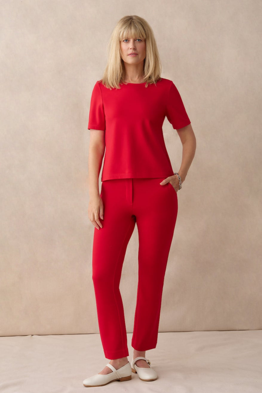 Woman wearing a red outfit standing against a beige background