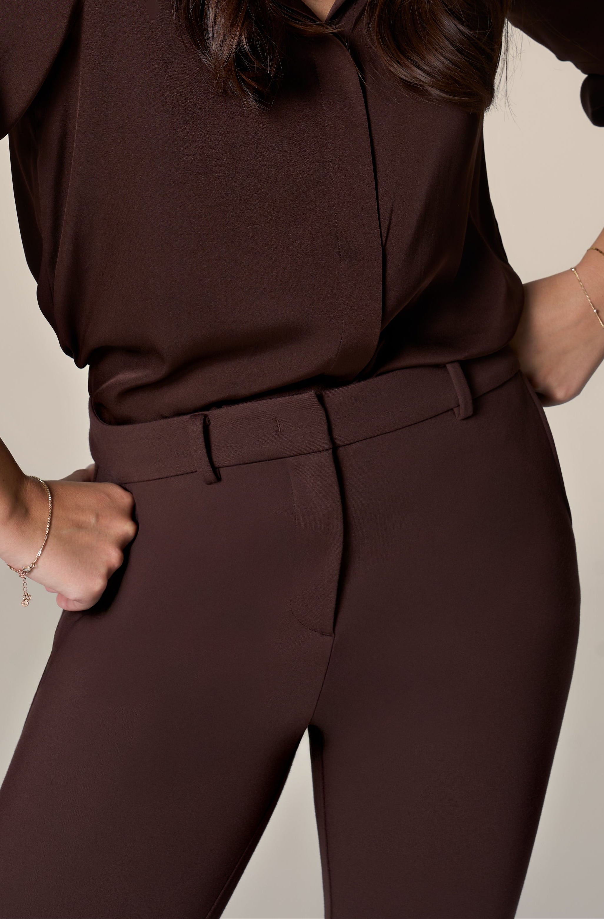 Woman wearing brown pants and matching blouse on a white background