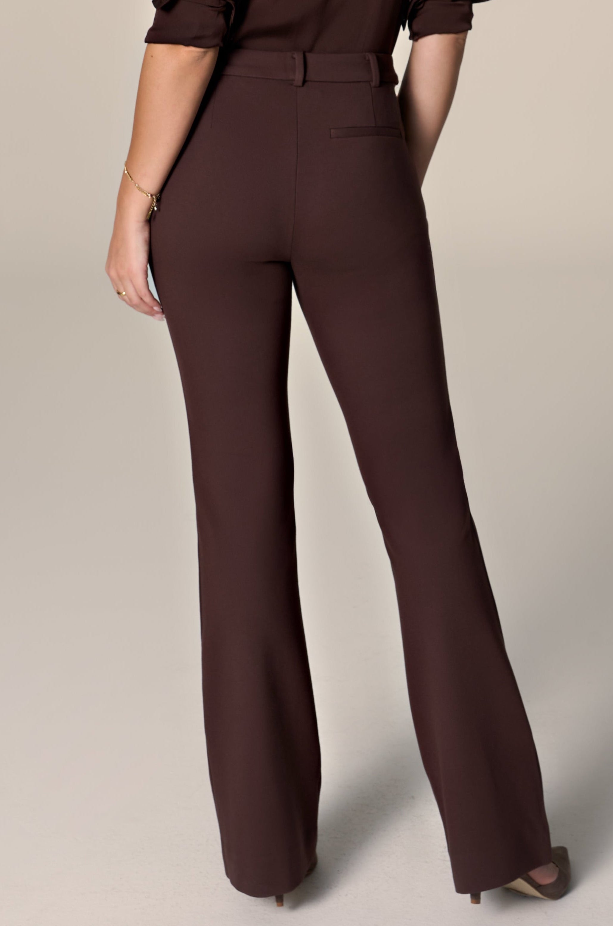 Woman wearing brown pants and matching blouse on a white background