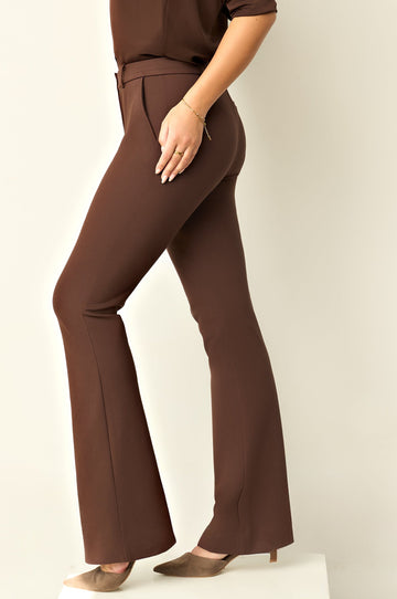 Woman wearing brown pants and matching blouse on a white background
