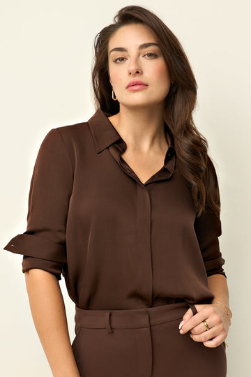 Woman wearing a brown silk blouse and matching pants against a beige background