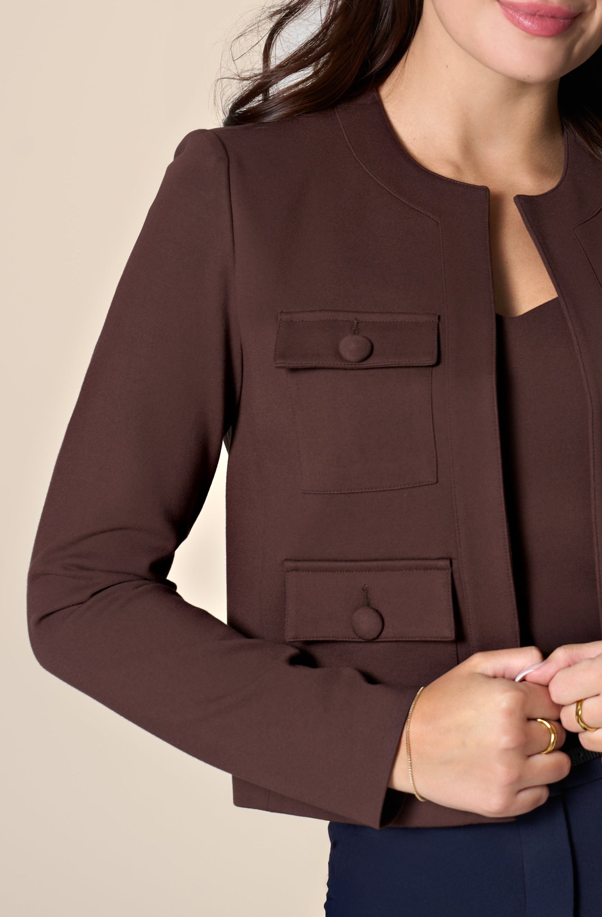 Woman wearing brown jacket on white background.