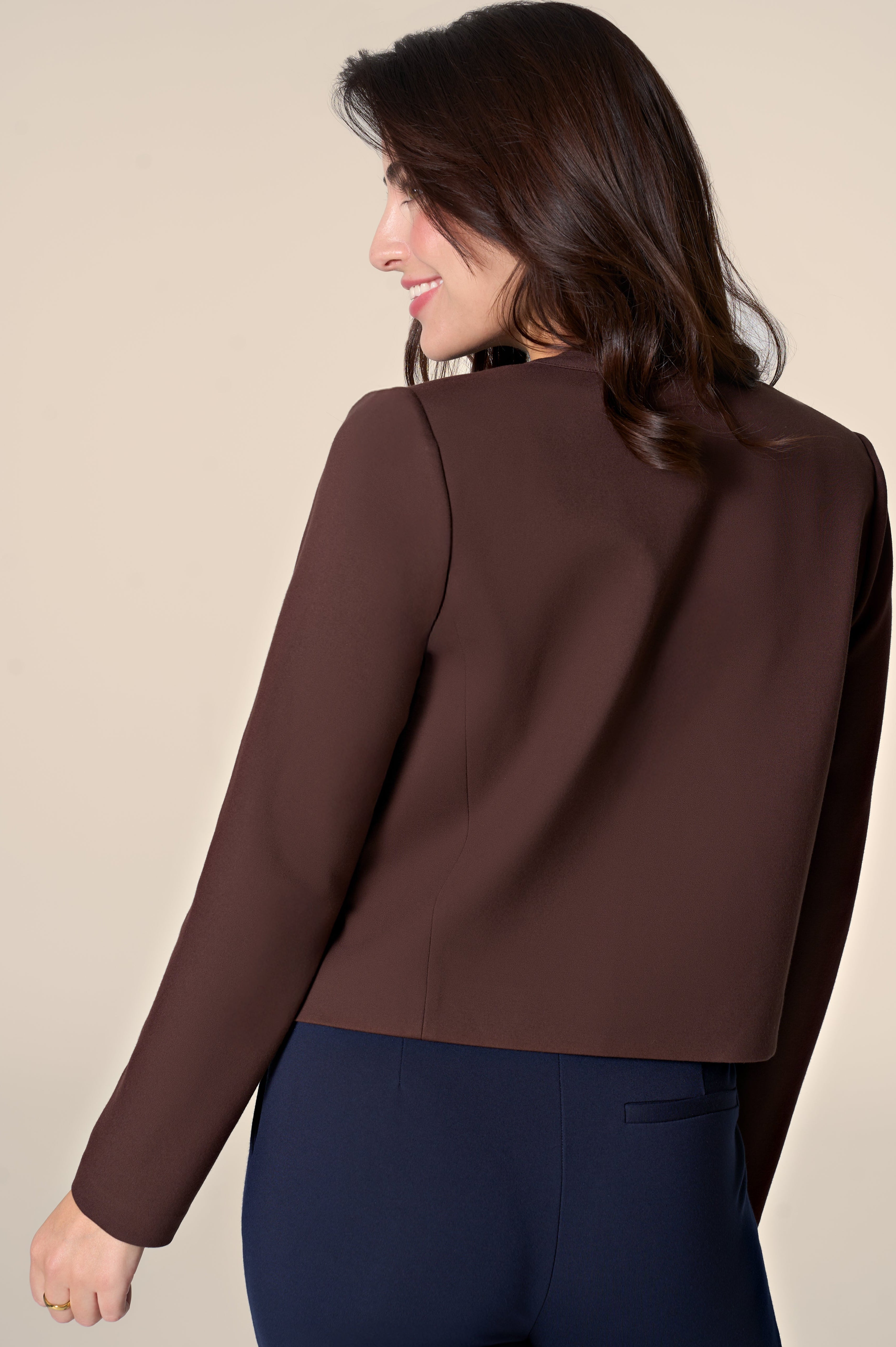 Woman wearing brown jacket on white background.