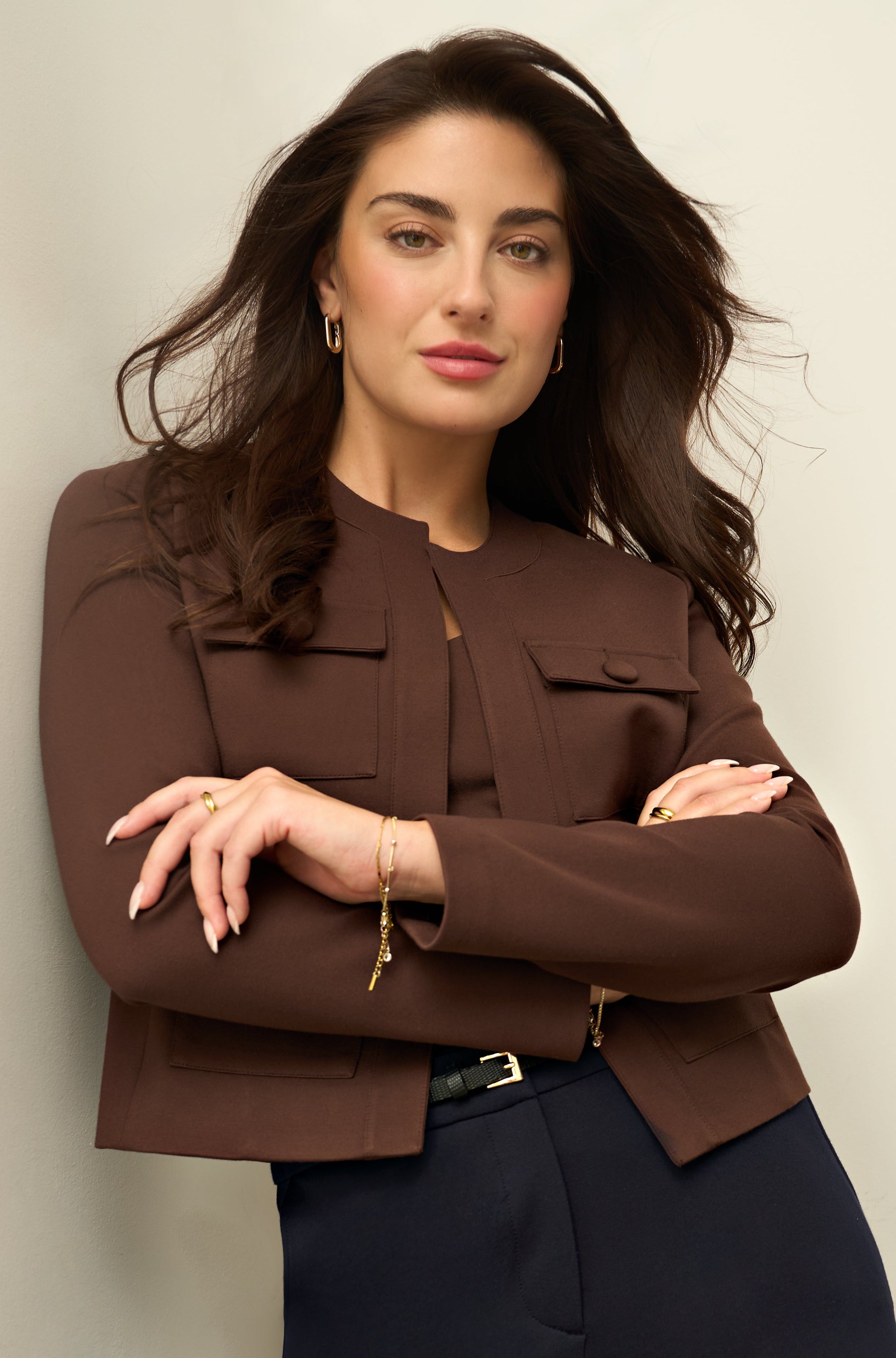 Woman wearing brown jacket on white background.