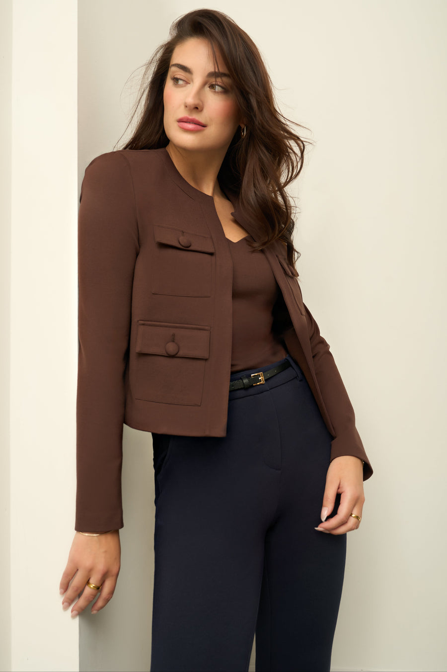 Woman wearing brown jacket on white background.
