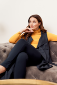 woman wearing orange turtle neck and black vest